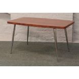 A retro rosewood effect dining table on chrome supports.