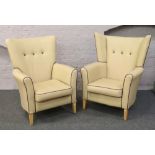 Two cream vinyl deep buttoned high back arm chairs.