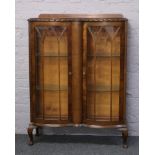 A 1940s carved walnut bow front display cabinet raised on cabriole supports.