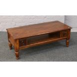 A rosewood two tier two drawer coffee table raised on turned supports.