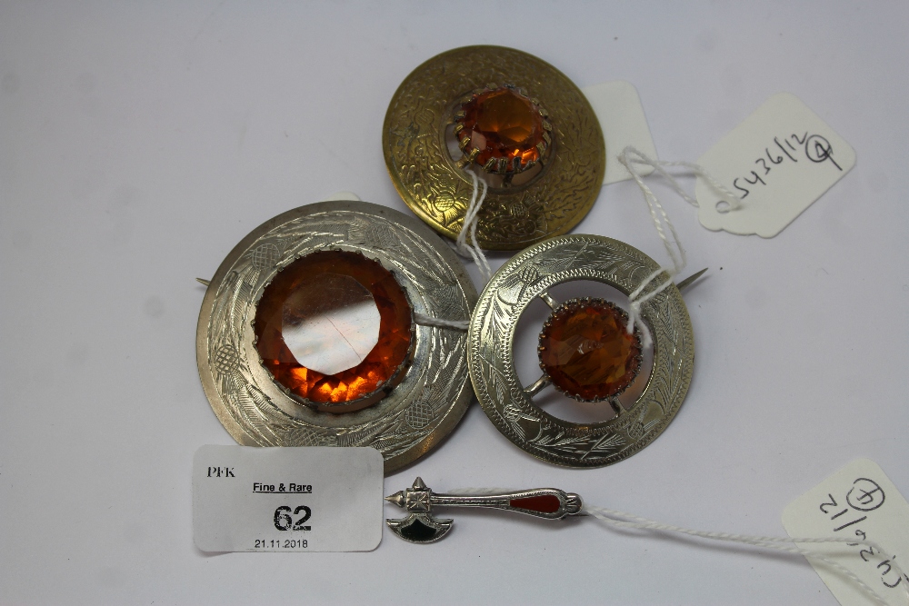 Three Scottish plated amber glass brooches and a silver miniature axe brooch