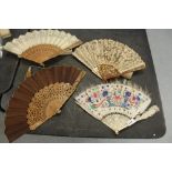 Two sandalwood and fabric fans, a pierced bone and painted feather fan and one other fan