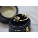 18ct gold sapphire and diamond cross over ring, size L, central sapphire approx 0.10ct, diamonds