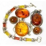 An assortment of amber and silver jewellery, including two pendants, a brooch, a pair of clip on