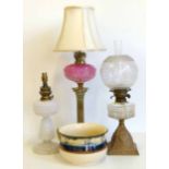 A brass oil lamp with a pink glass reservoir, a milk glass oil lamp and one other, also a Royal