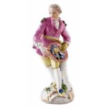 German figure of a Gentleman probably Meissen, modelled holding a hat of flowers, on scrolled