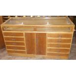 A 20th century oak shop haberdashery cabinet with sloping glazed display top having 10 drawers and 2