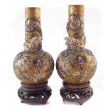 Pair of Japanese Satsuma vases, moulded with dragons and painted with immortals, with wood bases,