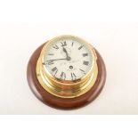 A mid 20th century brass ships bulkhead clock on mahogany backboard by F. W Elliott, Croydon. With