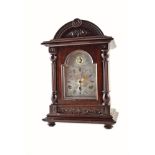 An Edwardian mahogany mantel clock. With barrel vaulted top and wood carved foliate motif in