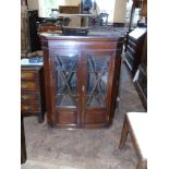 A 19th century oak and mahogany two-door glazed corner cupboard with shaped shelves and three