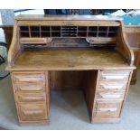 An early 20th century oak double pedestal roll-top desk, the base having 8 drawers, the tambour