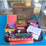 A wooden jewellery box containing an assortment of costume jewellery including brooches,