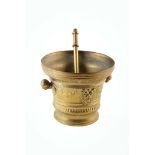 A large 19th century brass pestle and mortar. The mortar has swags of leaves and the faces of Pan or
