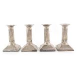 Four silver dwarf candlesticks by William Hutton & Sons , corinthian columns to square-stepped