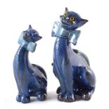 Two C.H. Brannam Barum pottery cats, with overall blue glazes, one with applied yellow plastic eyes,