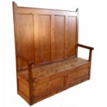 A pine settle, with four fielded panels to the back, the box seat with rising lid,