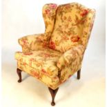 A pair of wing armchairs, raised on short cabriole legs,