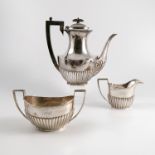 A matched silver three piece tea set, with gadrooned lower body and engraved with initials and date,