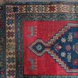 An Oriental runner, decorated with two blue ground lozenges to the red field, with double border,