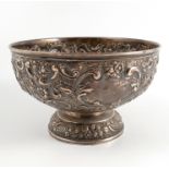 A silver circular pedestal bowl, heavily embossed with scrolls, flowers and lattice,