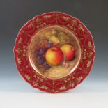 A Royal Worcester cabinet plate, the centre decorated with fruit to a mossy background by Seabright,