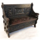 An Antique oak style settle, having three carved panels of figures and interior scene,
