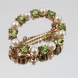 A cultured pearl and peridot brooch, of oval outline, alternate set in 9 carat gold, 3.1cm long, 5.