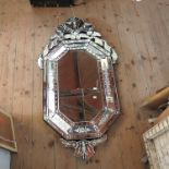 A modern Venetian style wall mirror, decorated with ornate scrolls and etched designs,