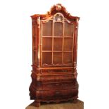 A reproduction French style walnut veneered display cabinet, having a shaped glazed upper section,