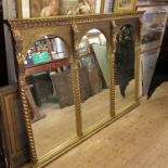 A large gilt mirror, having three arched plates, flanked by barley twist columns,