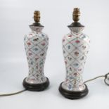 A pair of porcelain lamp bases, of baluster form, decorated with flowers and gilt to a white ground,