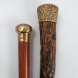 A walking stick, with 18ct gold plated top decorated with scrolls and a textured wooden shaft,