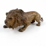 A cold painted bronze model, of a crouching lion, height 2.75ins, length 7.