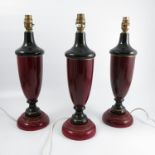 Three wooden lamp bases, of urn form, decorated in black and mottled red, height 17.