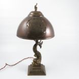 A brass table lamp, the column formed as a fish to a stepped square base with leaf decoration,