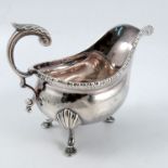A silver sauce boat, with scroll handle, gadrooned edge and raised on three scroll legs with shell