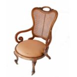 A Victorian cane back chair, with open scroll arms