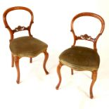 A pair of Victorian dining chairs, with carved lower bar to the backs and raised on cabriole legs,