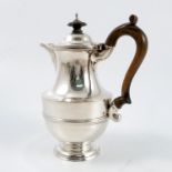 A silver hot water jug, of ribbed baluster form, with wooden scroll handle, raised on a circular
