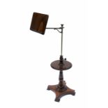 An Edwardian mahogany adjustable reading stand, with brass arm, circular shelf on a turned column