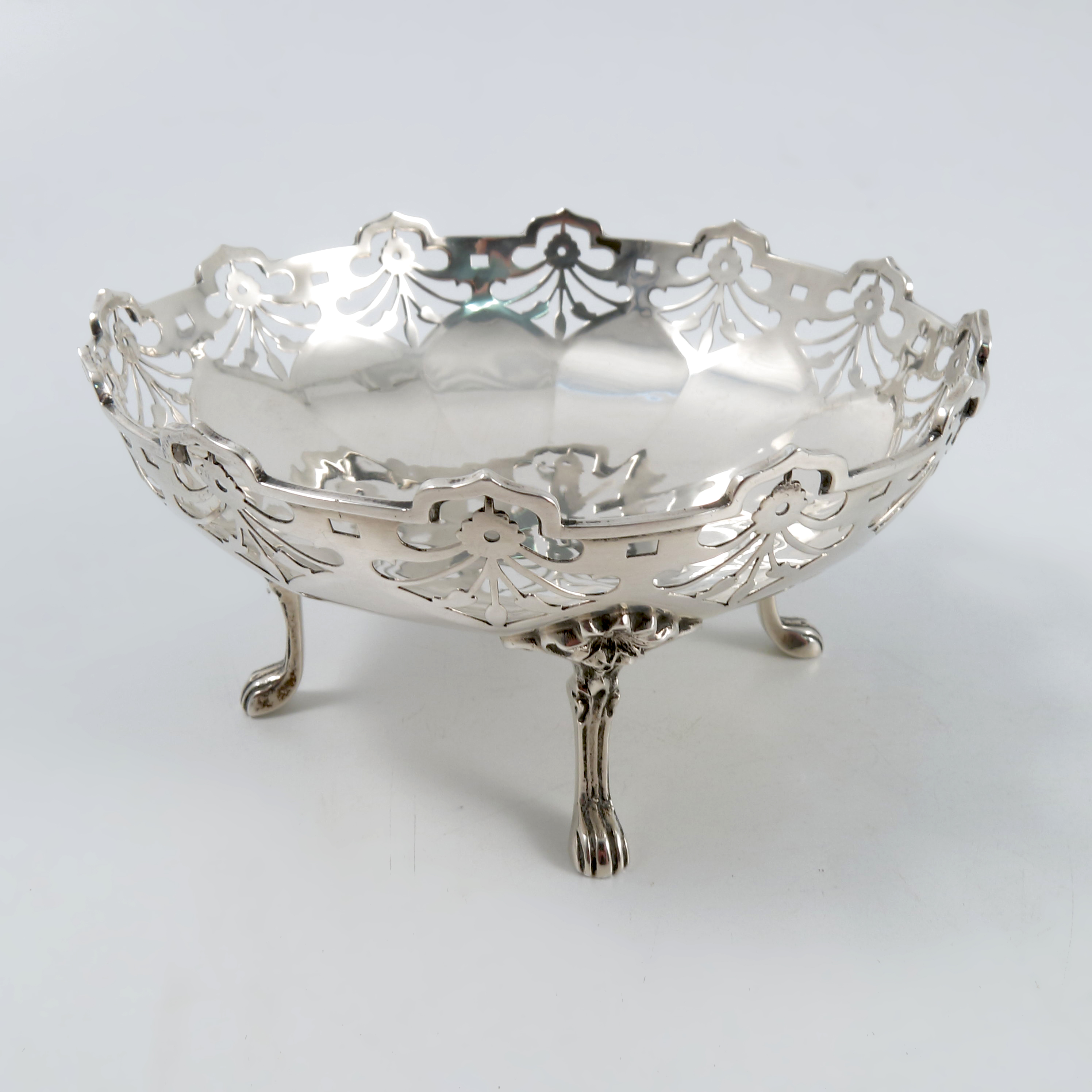 A silver dish, of shaped circular form with pierced edge, raised no four reeded legs and paw feet,