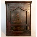 An 18th century mahogany corner cupboard, the painted panel door decorated with an armorial, masks