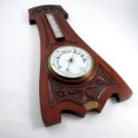 A mahogany cased aneroid barometer, with mercury filled thermometer, the case carved in the Art