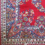 A rug, the red ground field decorated with floral swags, 58.5ins x 90ins