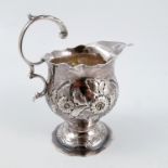 A Georgian silver jug, with shaped edge, the body embossed with flowers, leaves and scrolls,