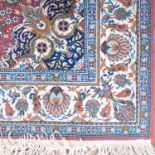 A rug, with pink ground decorated with a floral motif to the centre, spandrels and white ground