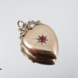 A heart locket, unmarked, star set with a red stone to the centre, seed pearl set bow surmount, 2.