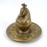 A Victorian brass inkwell, the hinged inkwell formed as an Egyptian head, on a circular dish