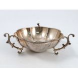 A silver bowl, the shaped circular bowl having three scroll handles to small curved feet, engraved